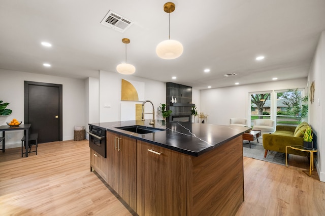 2114 Lazybrook Dr, Houston, TX 77008 - kitchen with a sink, dark countertops, a center island with sink, light wood-style flooring, and recessed lighting