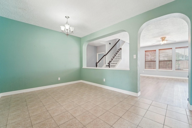 3339 Legends Creek Dr, Spring, TX 77386 - spare room featuring a textured ceiling, arched walkways, a chandelier, tile patterned flooring, and baseboards
