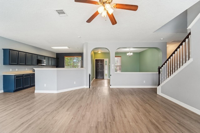 3339 Legends Creek Dr, Spring, TX 77386 - unfurnished living room with light wood finished floors, arched walkways, a textured ceiling, and baseboards