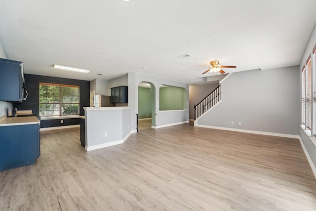 3339 Legends Creek Dr, Spring, TX 77386 - unfurnished living room with a textured ceiling, baseboards, ceiling fan, arched walkways, and light wood-style flooring