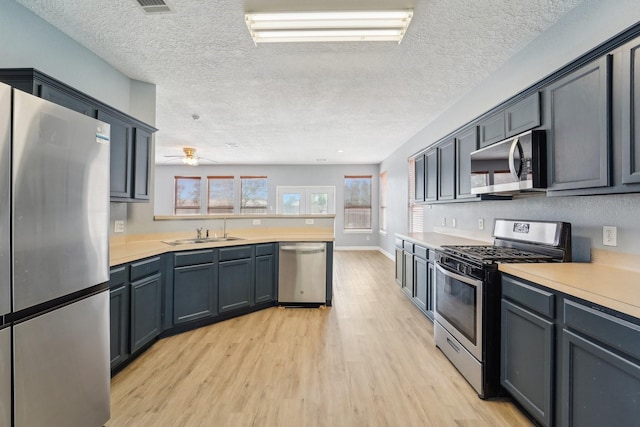 3339 Legends Creek Dr, Spring, TX 77386 - kitchen featuring appliances with stainless steel finishes, light wood-style flooring, light countertops, a peninsula, and a sink