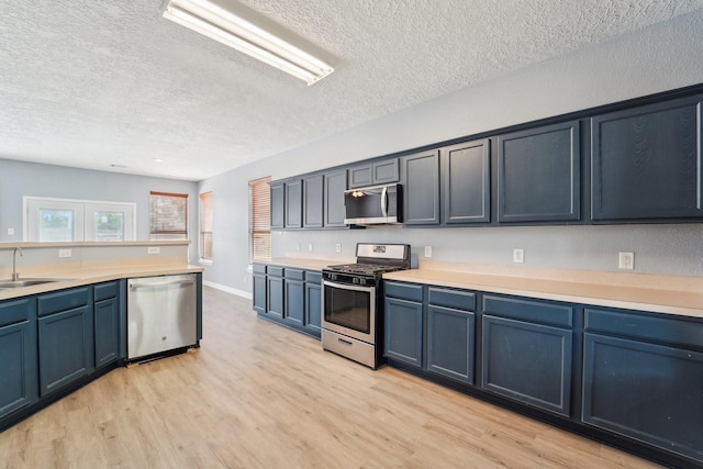 3339 Legends Creek Dr, Spring, TX 77386 - kitchen with stainless steel appliances, a textured ceiling, a sink, light wood-style floors, and light countertops