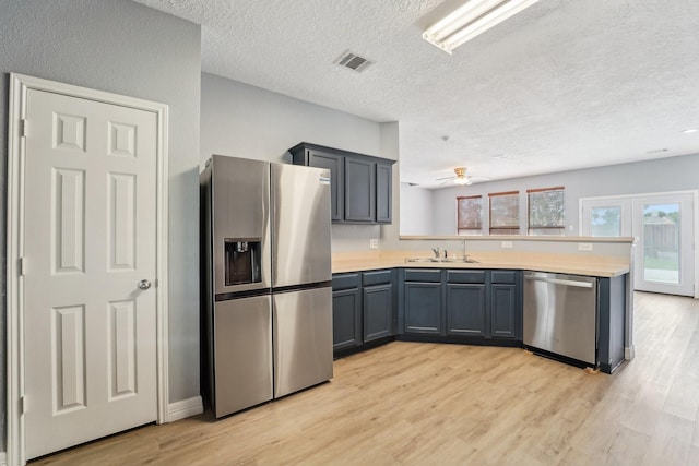 3339 Legends Creek Dr, Spring, TX 77386 - kitchen featuring stainless steel appliances, a peninsula, a sink, light wood-style floors, and a textured ceiling