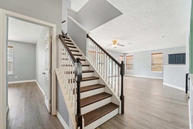 3339 Legends Creek Dr, Spring, TX 77386 - staircase featuring a textured ceiling, ceiling fan, wood finished floors, plenty of natural light, and baseboards