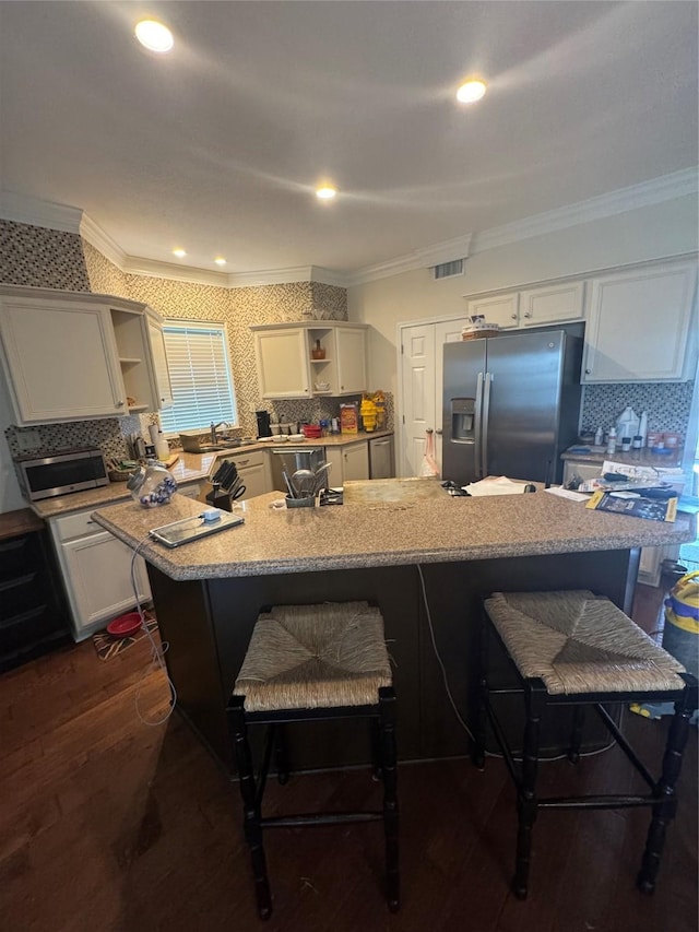 12811 E Conquistador Dr, Galveston, TX 77554 - kitchen featuring open shelves, stainless steel appliances, ornamental molding, a kitchen bar, and dark wood finished floors
