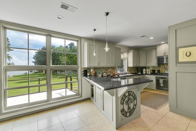 19727 Country Lake Dr, Magnolia, TX 77355 - kitchen with black oven, stainless steel microwave, a peninsula, decorative backsplash, and hanging light fixtures