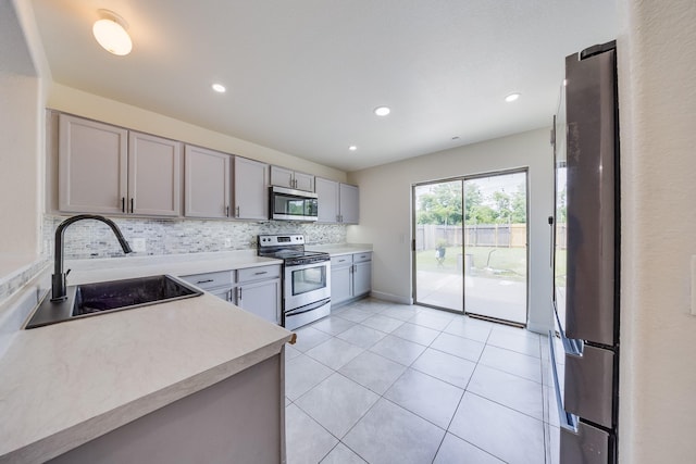19314 Cactus Thorn Dr, Cypress, TX 77433 - kitchen featuring stainless steel appliances, gray cabinetry, a sink, light countertops, and backsplash