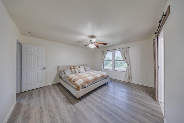 19314 Cactus Thorn Dr, Cypress, TX 77433 - bedroom featuring wood finished floors, baseboards, a barn door, and a ceiling fan