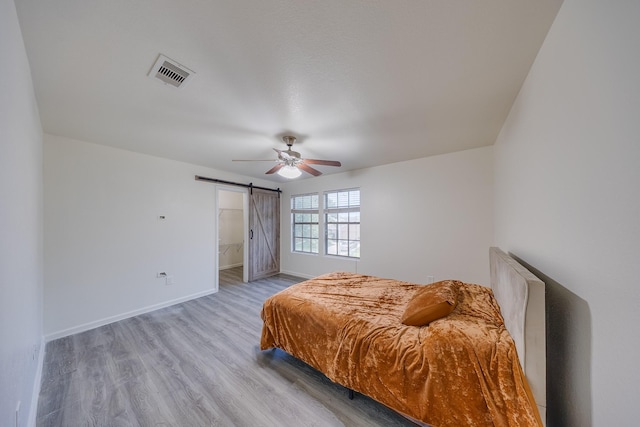 19314 Cactus Thorn Dr, Cypress, TX 77433 - bedroom featuring light wood-type flooring, a barn door, baseboards, and a ceiling fan
