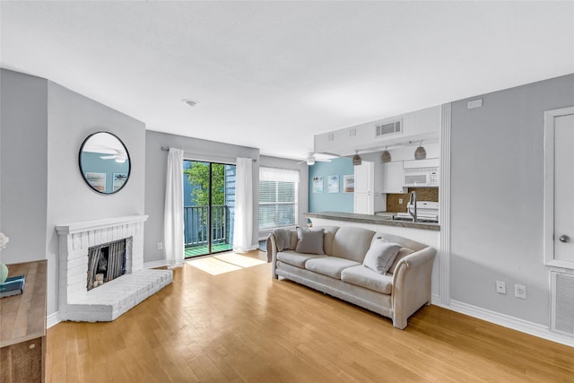 3220 69th St Unit K6, Galveston, TX 77551 - living area with light wood-style flooring, a brick fireplace, baseboards, and ceiling fan