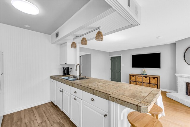 3220 69th St Unit K6, Galveston, TX 77551 - kitchen featuring a sink, a peninsula, light wood-style floors, and a breakfast bar