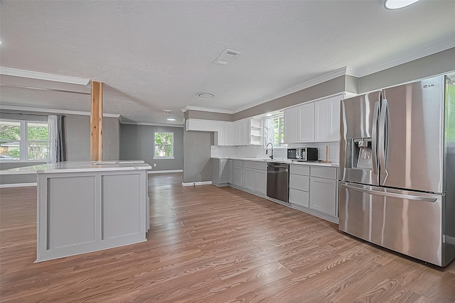 11903 Atwell Dr, Houston, TX 77035 - kitchen featuring appliances with stainless steel finishes, ornamental molding, light countertops, light wood-style floors, and healthy amount of natural light