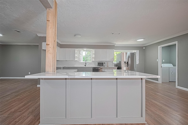 11903 Atwell Dr, Houston, TX 77035 - kitchen featuring appliances with stainless steel finishes, washer and dryer, ornamental molding, white cabinetry, and baseboards