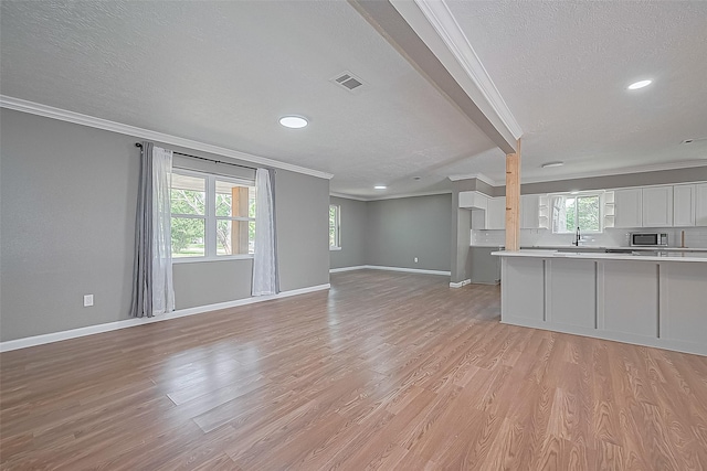 11903 Atwell Dr, Houston, TX 77035 - unfurnished living room featuring crown molding, a textured ceiling, baseboards, light wood finished floors, and recessed lighting