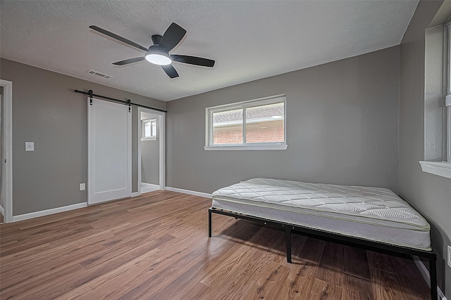11903 Atwell Dr, Houston, TX 77035 - bedroom featuring a barn door, light wood-style flooring, baseboards, and ceiling fan