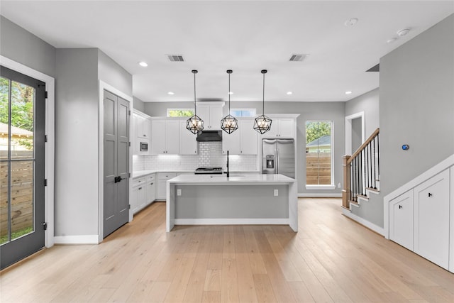 1412 Weiss St, Houston, TX 77009 - kitchen with stainless steel fridge with ice dispenser, light countertops, decorative backsplash, baseboards, and white cabinetry