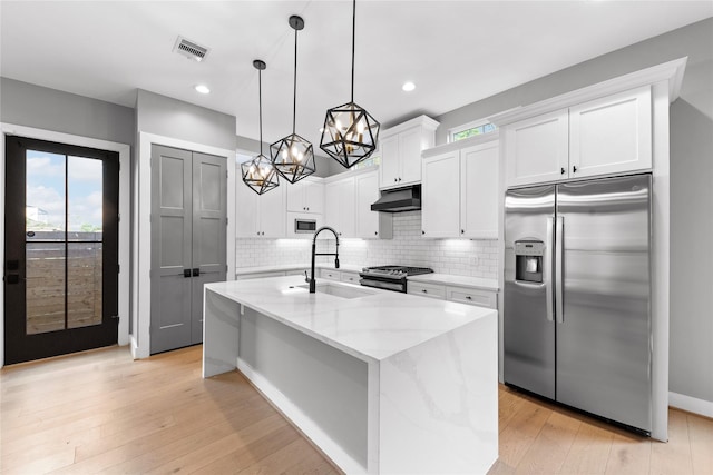 1412 Weiss St, Houston, TX 77009 - kitchen featuring stainless steel appliances, a sink, under cabinet range hood, a chandelier, and white cabinets