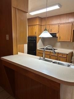 5005 Oak Ln, Texas City, TX 77591 - kitchen with a sink, brown cabinetry, light countertops, and hanging light fixtures