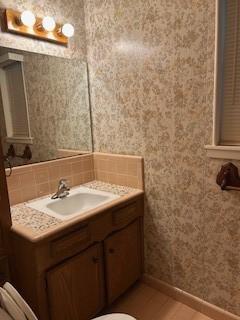 5005 Oak Ln, Texas City, TX 77591 - bathroom with wallpapered walls, vanity, and baseboards