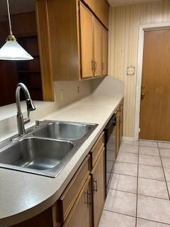 5005 Oak Ln, Texas City, TX 77591 - kitchen featuring a sink, black dishwasher, light tile patterned floors, decorative light fixtures, and brown cabinetry