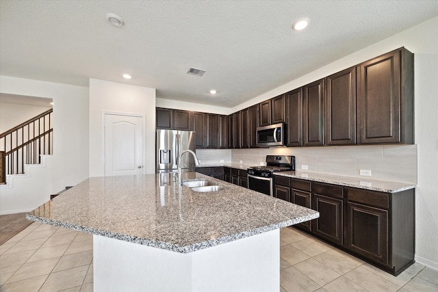 17303 Rock Willow Ln, Tomball, TX 77377 - kitchen featuring appliances with stainless steel finishes, a sink, light stone counters, dark brown cabinets, and recessed lighting