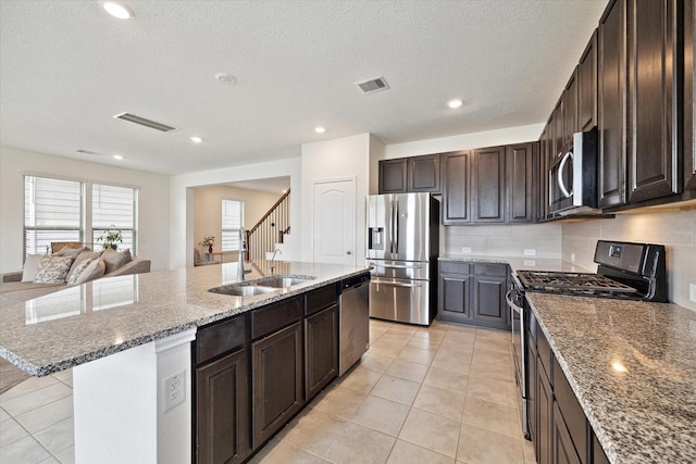 17303 Rock Willow Ln, Tomball, TX 77377 - kitchen with stainless steel appliances, an island with sink, a sink, decorative backsplash, and dark brown cabinets
