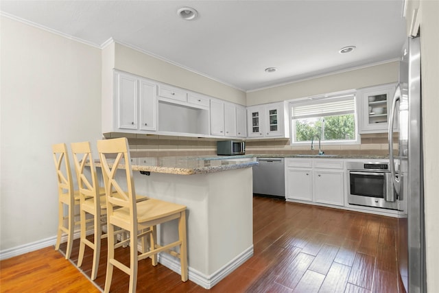 3641 Deal St, Houston, TX 77025 - kitchen featuring stainless steel appliances, a sink, a peninsula, glass insert cabinets, and ornamental molding
