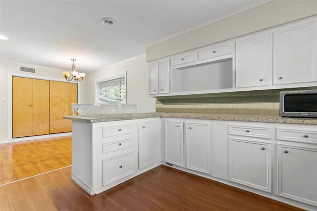 3641 Deal St, Houston, TX 77025 - kitchen featuring ornamental molding, white cabinets, a peninsula, a chandelier, and dark wood-style floors