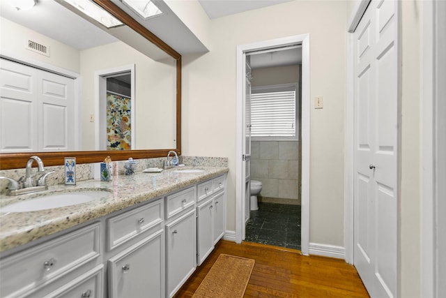 3641 Deal St, Houston, TX 77025 - bathroom with toilet, wood finished floors, double vanity, a skylight, and baseboards