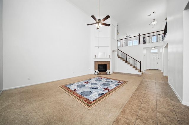 4663 Rockton Hills Ln, Sugar Land, TX 77479 - unfurnished living room with a high ceiling, a ceiling fan, a tiled fireplace, baseboards, and stairs