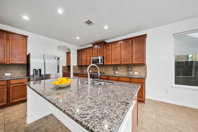 4663 Rockton Hills Ln, Sugar Land, TX 77479 - kitchen featuring appliances with stainless steel finishes, a sink, arched walkways, dark stone counters, and backsplash
