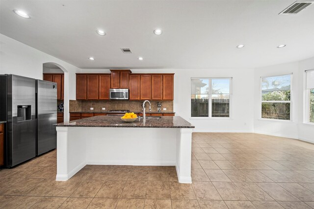 4663 Rockton Hills Ln, Sugar Land, TX 77479 - kitchen featuring stainless steel appliances, tasteful backsplash, dark stone countertops, a kitchen island with sink, and light tile patterned flooring