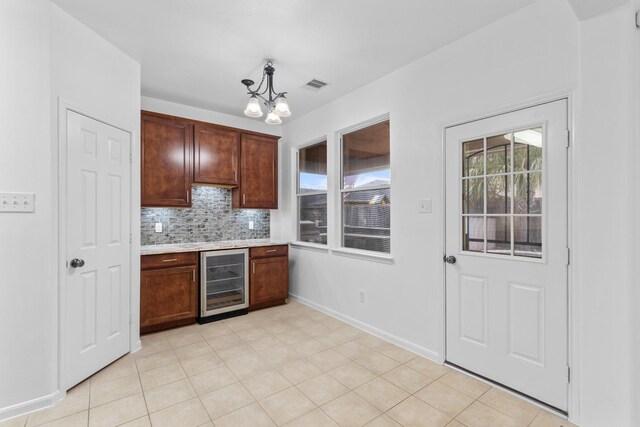 kitchen with wine cooler, a chandelier, light countertops, tasteful backsplash, and baseboards