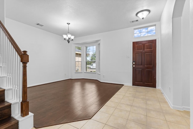 entryway featuring stairway, a chandelier, baseboards, and light tile patterned floors