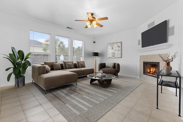 living area featuring light tile patterned floors, a ceiling fan, a tile fireplace, and baseboards
