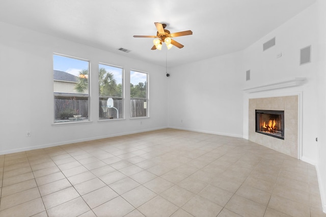 unfurnished living room featuring a ceiling fan, a tile fireplace, light tile patterned floors, and baseboards
