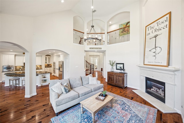 6338 Collina Springs Ct, Houston, TX 77041 - living area featuring dark wood finished floors, a glass covered fireplace, a chandelier, arched walkways, and high vaulted ceiling