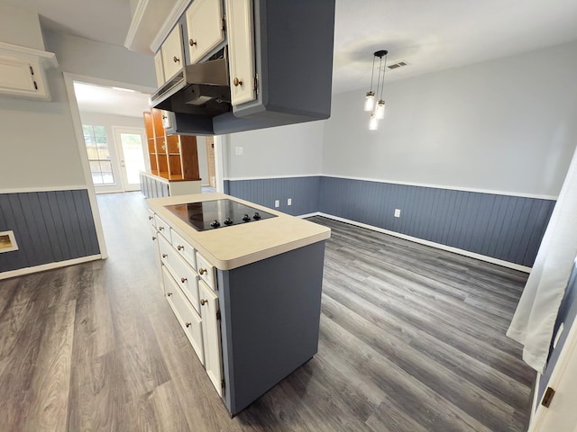 16007 Sailfin St, Crosby, TX 77532 - kitchen with black electric cooktop, wainscoting, dark wood-style floors, under cabinet range hood, and white cabinets