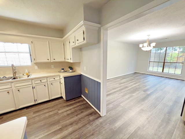 16007 Sailfin St, Crosby, TX 77532 - kitchen featuring a sink, a chandelier, light wood-type flooring, light countertops, and white cabinets