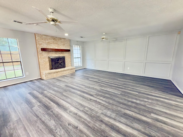 16007 Sailfin St, Crosby, TX 77532 - unfurnished living room featuring a ceiling fan, a textured ceiling, wood finished floors, a decorative wall, and a brick fireplace