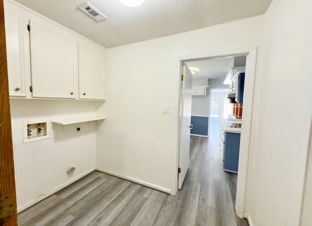 16007 Sailfin St, Crosby, TX 77532 - laundry area featuring cabinet space, hookup for an electric dryer, washer hookup, light wood-type flooring, and baseboards