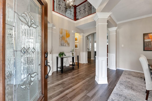 31 Brywood Pl, The Woodlands, TX 77382 - entrance foyer featuring ornate columns, dark wood-style flooring, arched walkways, a chandelier, and crown molding