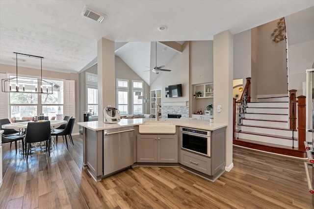 31 Brywood Pl, The Woodlands, TX 77382 - kitchen featuring stainless steel appliances, a sink, a chandelier, gray cabinets, and light wood finished floors