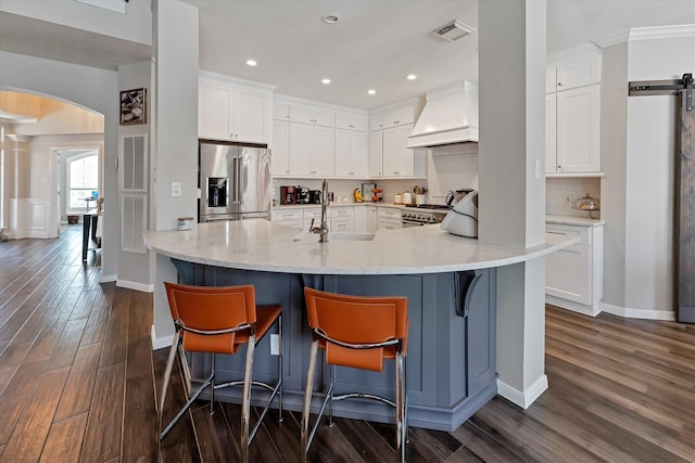 31 Brywood Pl, The Woodlands, TX 77382 - kitchen featuring stainless steel fridge, custom exhaust hood, a sink, arched walkways, and dark wood finished floors