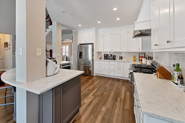31 Brywood Pl, The Woodlands, TX 77382 - kitchen with appliances with stainless steel finishes, premium range hood, decorative backsplash, recessed lighting, and dark wood-type flooring