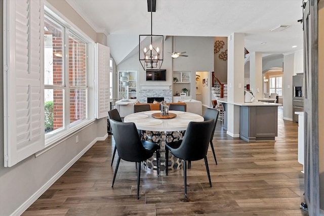 31 Brywood Pl, The Woodlands, TX 77382 - dining area featuring a fireplace, stairway, baseboards, arched walkways, and dark wood-type flooring