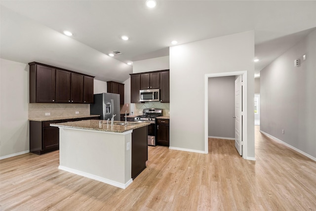 513 Bonnerville Ln, Magnolia, TX 77354 - kitchen featuring stainless steel appliances, dark brown cabinetry, decorative backsplash, light wood finished floors, and lofted ceiling