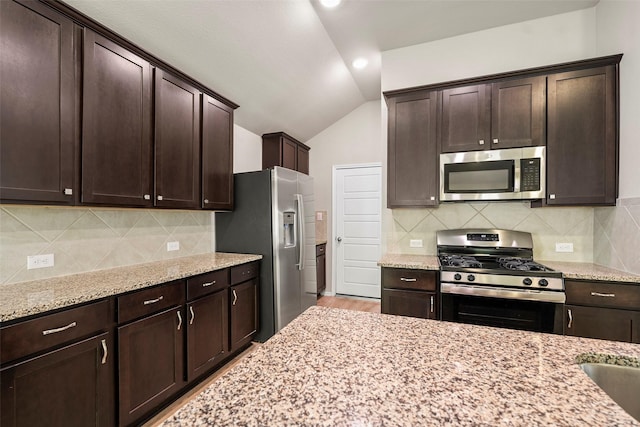513 Bonnerville Ln, Magnolia, TX 77354 - kitchen with stainless steel appliances, lofted ceiling, dark brown cabinets, light stone countertops, and backsplash