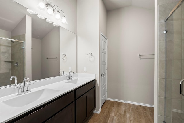 513 Bonnerville Ln, Magnolia, TX 77354 - bathroom featuring wood finished floors, a shower stall, vaulted ceiling, double vanity, and baseboards
