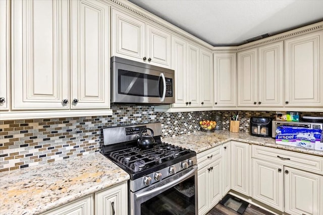 kitchen with stainless steel appliances, tasteful backsplash, and light stone countertops